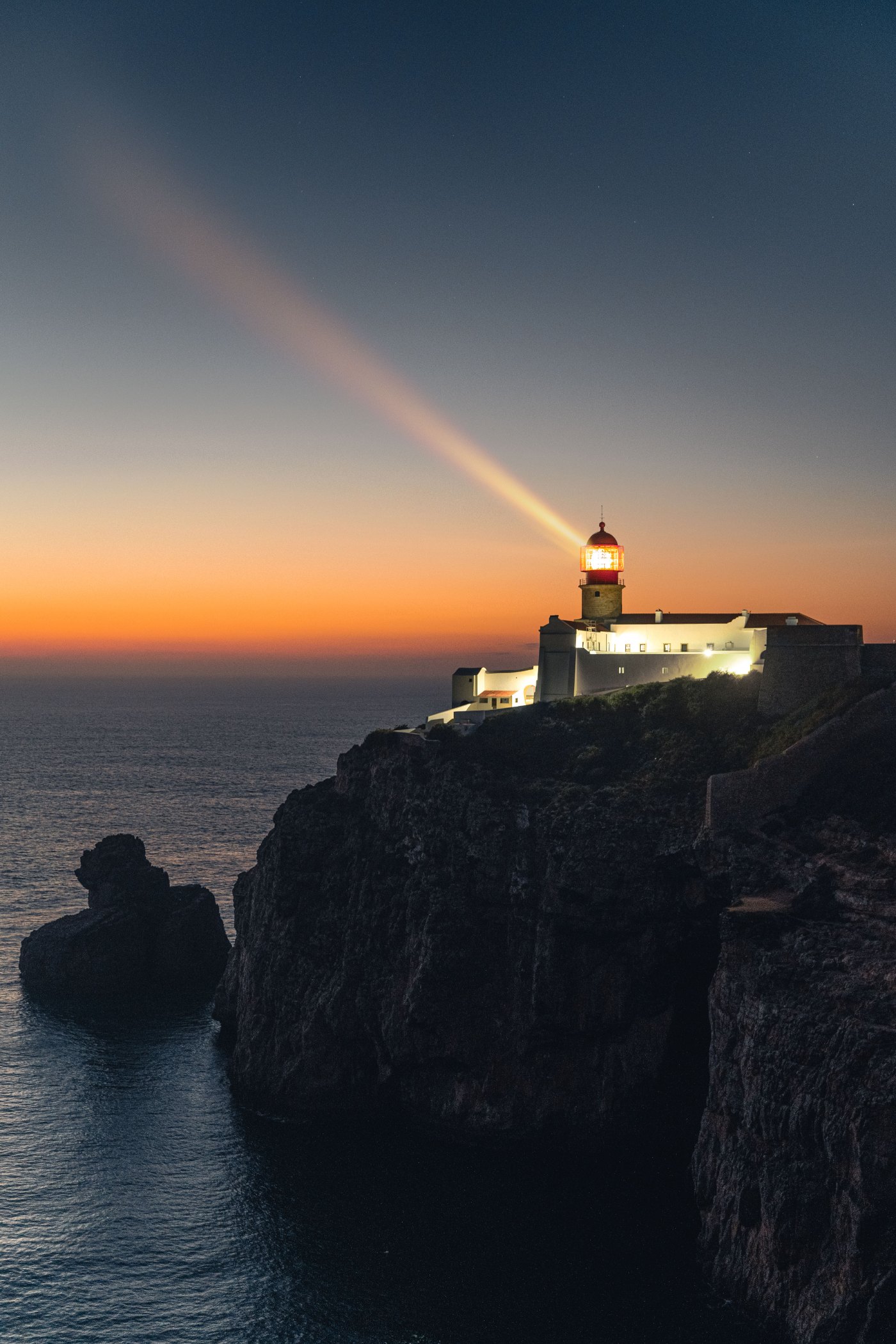 Lighthouse beam at dusk over the ocean