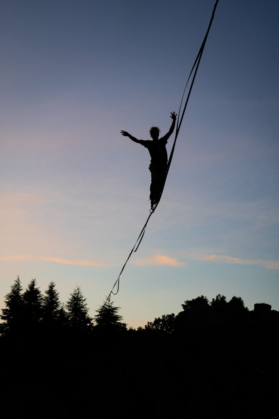 Person balancing on a highline at sunset